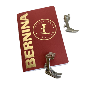 Red notebook with 'BERNINA' and 'Little Book of Feet' text, accompanied by metal sewing footplates on a white background. Red notebook with 'BERNINA' and 'Little Book of Feet' text, accompanied by metal sewing footplates on a white background.