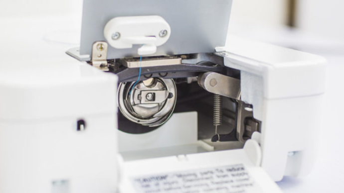 Close-up of a baby lock accomplish sewing machine's needle and mechanism on a white background
