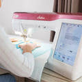 Person using a sewing machine with a digital display on a table.
