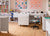 Craft room with sewing tables, chairs, and colorful wall art.