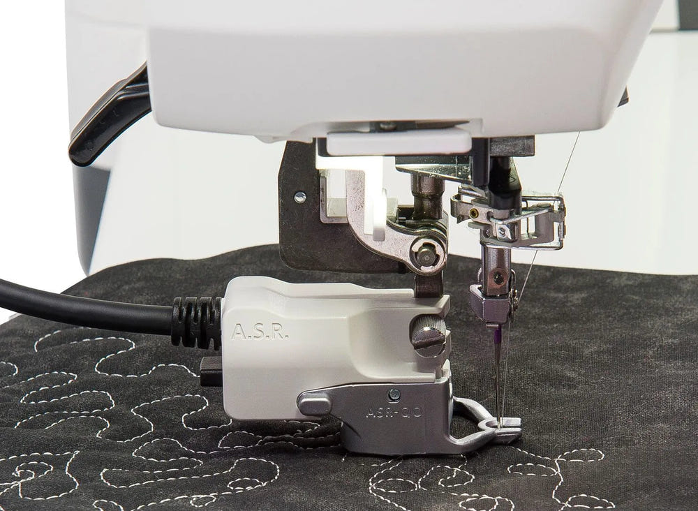Close-up of a white sewing machine with a metallic press foot and a white A.S.R.