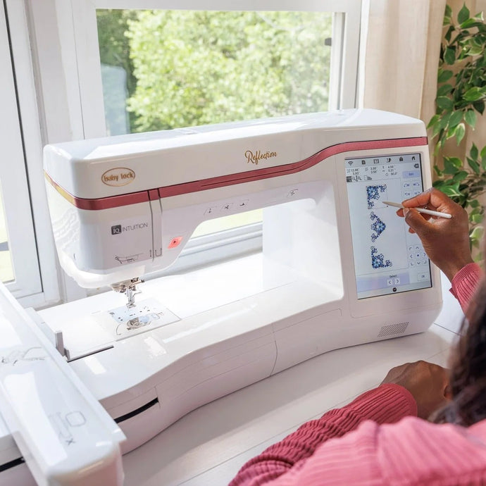 Person using a sewing machine with a digital display in a bright room with a window and plant.