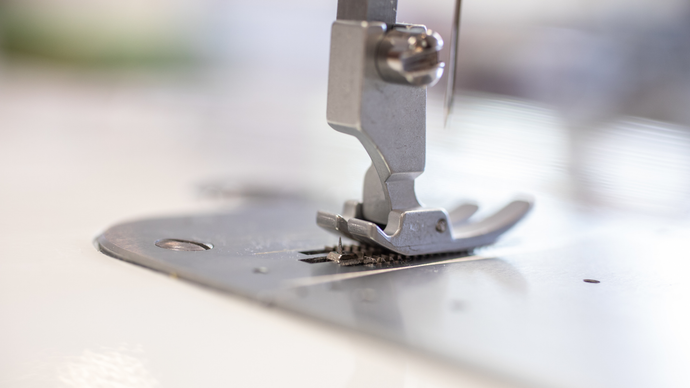 Close-up of a baby lock accomplish sewing machine needle and presser foot on a blurred background