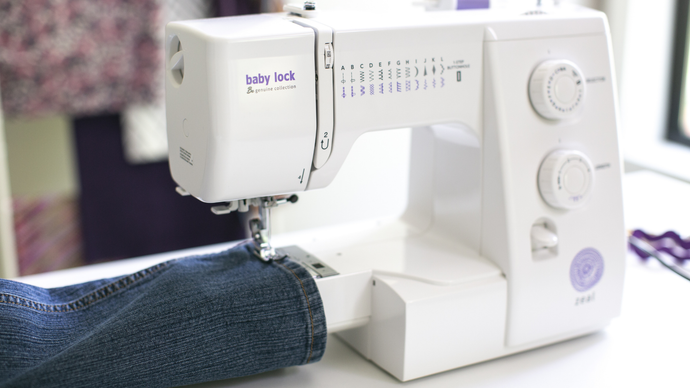 Baby Lock Zeal sewing machine with 'baby lock' branding on a table with denim fabric.
